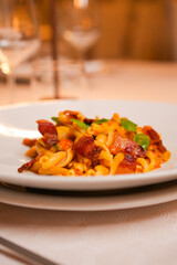 Piatto di Pasta con crema di pomodoro, basilico fresco e pancetta croccante servito in un ristorante elegante