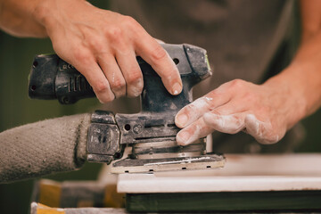 Maler setzt Schleifgerät am Fenster ein