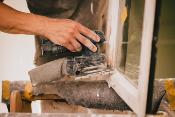 Maler setzt Schleifgerät am Fenster ein