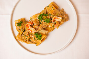 Paccheri con gamberi, carciofi e prezzemolo serviti in un ristorante come primo piatto