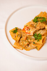 Paccheri con gamberi, carciofi e prezzemolo serviti in un ristorante come primo piatto