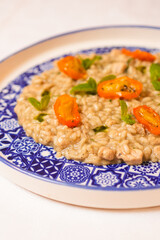 Risotto mantecato con burro e asparagi, guarnito con pomodori gialli arrostiti servito in un ristorante elegante