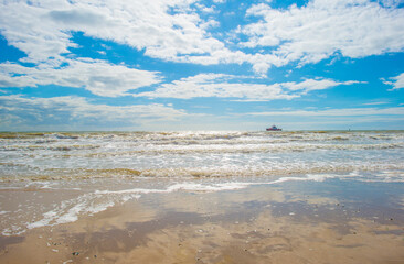 Sand  beach along a sea under a blue cloudy sky in bright sunlight in summer, Walcheren, Zeeland, the Netherlands, July, 2024