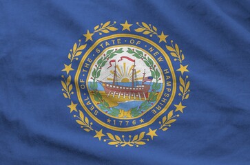 New Hampshire US state flag depicted on folded wavy fabric of old cloth close up