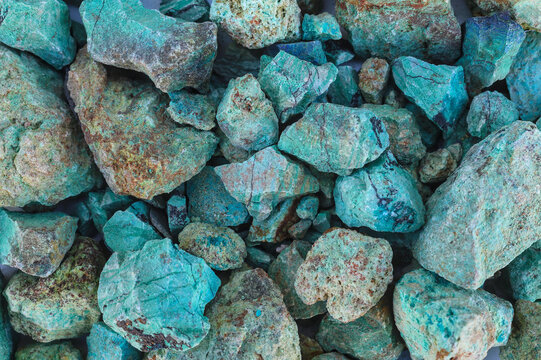 Blue green copper (Cu) oxide ore, held in hand, against background of ore that is out of focus. Mining.