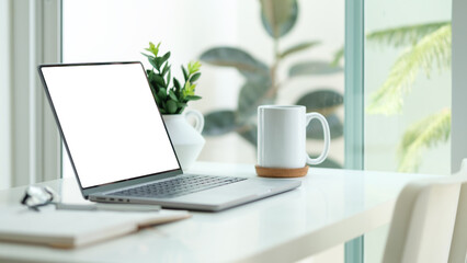 Mockup laptop with empty display, coffee cup, books white table.