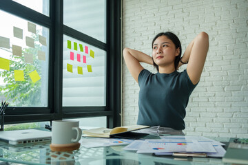 Fototapeta premium Satisfied young businesswoman stretching her arms in the air, relaxing at workplace.