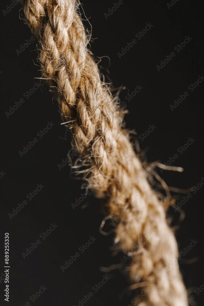 Poster a close-up view of a rope on a dark, matte finish background