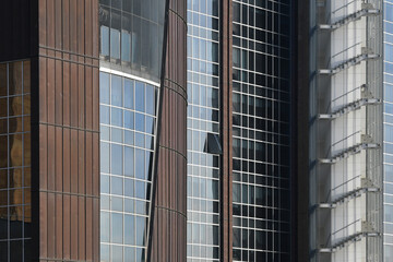 Fototapeta premium Architecture of a modern office building, construction background. Facade glass windows of a corporate center. Modern commercial buildings exterior.