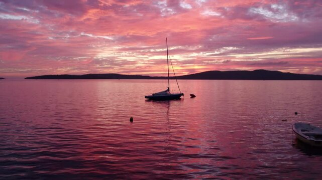 Aerial view of colourful sailboat sailing in serene sea at sunset, Krapanj Island, Croatia.