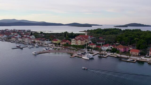 Aerial view of coastal town Krapanj with boats cruising in the sea at sunset, Sibenik, Croatia.