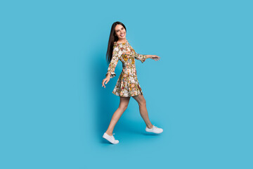 Full length photo of cheerful good mood lady dressed print clothes walking empty space isolated blue color background