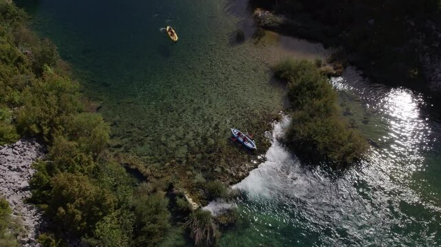 Aerial view of serene river with kayak and boat, lush greenery and rocky terrain, Zrmanja, Croatia.