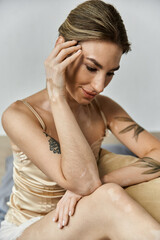 Obraz premium A young woman with vitiligo and tattoos sits in her modern apartment bedroom, lost in thought.