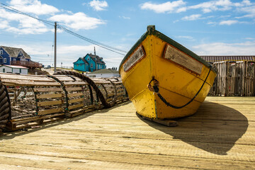 dory and lobster traps (traditional wooden construction) on a dock outside a fish shack in peggy's cove nova scotia in bright sunlight