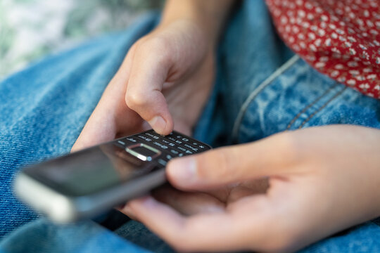 Close Up Of Teenage Girl Using Basic Dumbphone Push Button Mobile Phone For Messaging With No Online Connection