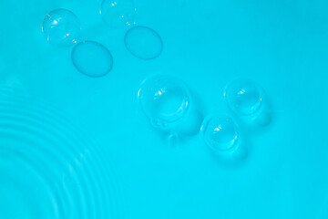Floating Bubbles in Blue. A calming scene of transparent floating bubbles in clear blue liquid with gentle ripples.