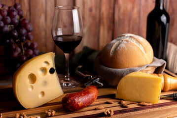 glass of red wine with wine bottle with cheese board country bread wooden board fresh grapes knife and cork opener and bottle