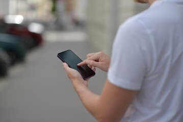 A man on the street using a smartphone. Mobile phone in hands close-up.
