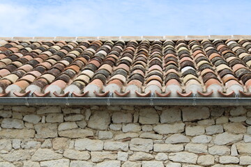 Toiture en tuiles canal ou romane avec crochet sur maison en pierre ancienne