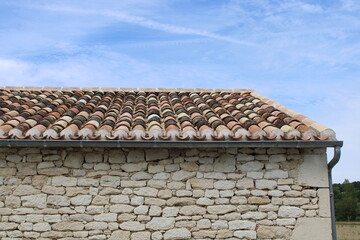 Toiture en tuiles canal ou romane avec crochet sur maison en pierre ancienne
