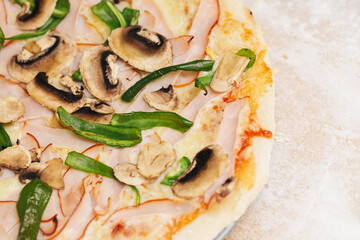 Delicious homemade pizza with ham, bell pepper, and mushrooms on wooden cutting board. Freshly baked pizza with flour all around. Do it yourself piza at home background. Big plate of thin crust pizza.