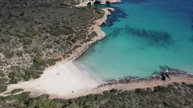 Aerial view of serene beach bay with azure waters and rocky cliffs, Cala Varques, Mallorca, Spain.