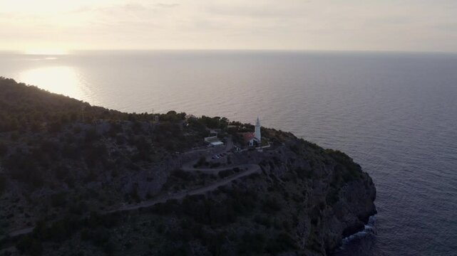 Aerial view of sunset over Balearic Sea with lighthouse and cliff, Soller, Mallorca, Spain.
