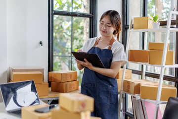 Portrait business woman smile and use laptop checking information on parcel shipping box before send to customer. Entrepreneur small business working at home. SME business online marketing.