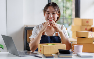 Portrait business woman smile and use laptop checking information on parcel shipping box before send to customer. Entrepreneur small business working at home. SME business online marketing.