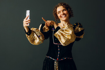 Portrait of a young aristocratic woman doing photo selfie with mobile phone and dressed in a medieval dress