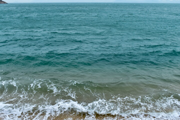 Close-up of soft waves sand beach and blue sea. Texture of water, white foam waves. Seascape, Sea background, Sea water with copy space, summer vacation concept. 