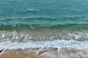 Close-up of soft waves sand beach and blue sea. Texture of water, white foam waves. Seascape, Sea background, Sea water with copy space, summer vacation concept. 