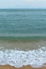 Close-up of soft waves sand beach and blue sea. Texture of water, white foam waves. Seascape, Sea background, Sea water with copy space, summer vacation concept. 