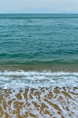 Close-up of soft waves sand beach and blue sea. Texture of water, white foam waves. Seascape, Sea background, Sea water with copy space, summer vacation concept. 