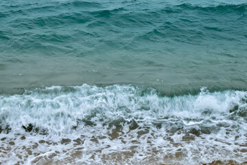 Close-up of soft waves sand beach and blue sea. Texture of water, white foam waves. Seascape, Sea background, Sea water with copy space, summer vacation concept. 