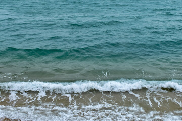 Close-up of soft waves sand beach and blue sea. Texture of water, white foam waves. Seascape, Sea background, Sea water with copy space, summer vacation concept. 