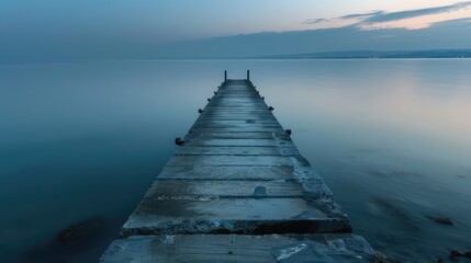 Obraz premium A long pier stretching out into a calm sea at dawn