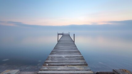 Obraz premium A long pier stretching out into a calm sea at dawn
