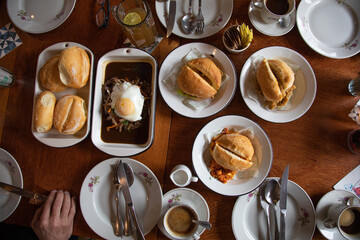 Peruvian breakfast food table with lomo saltado and pejerrey sandwich