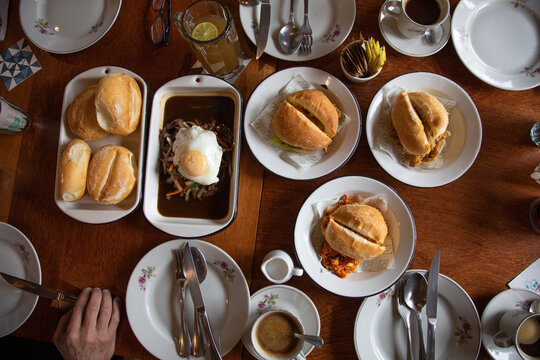 Peruvian breakfast food table with lomo saltado and pejerrey sandwich
