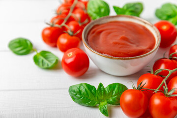 Tomato paste, sauce, ketchup in a bowl and cherry tomatoes with fresh basil leaves on a textured wooden background. Vitamins and detox diet. Vegetable and vegetarian food. Space for text. Copy space.