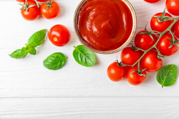 Tomato paste, sauce, ketchup in a bowl and cherry tomatoes with fresh basil leaves on a textured...