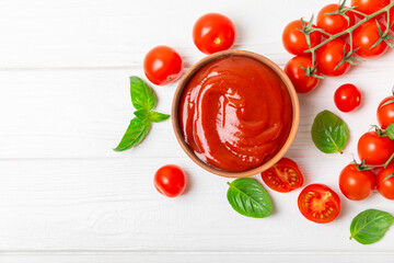 Tomato paste, sauce, ketchup in a bowl and cherry tomatoes with fresh basil leaves on a textured...