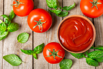 Tomato paste, sauce, ketchup in a bowl and cherry tomatoes with fresh basil leaves on a textured...