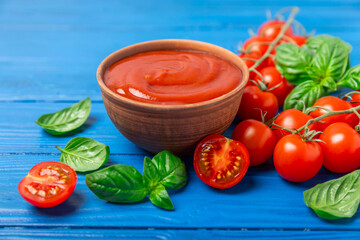Tomato paste, sauce, ketchup in a bowl and cherry tomatoes with fresh basil leaves on a textured wooden background. Vitamins and detox diet. Vegetable and vegetarian food. Space for text. Copy space.
