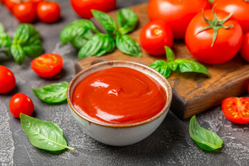 Tomato paste, sauce, ketchup in a bowl and cherry tomatoes with fresh basil leaves on a textured wooden background. Vitamins and detox diet. Vegetable and vegetarian food. Space for text. Copy space.