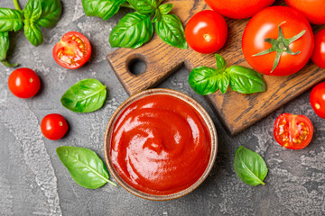 Tomato paste, sauce, ketchup in a bowl and cherry tomatoes with fresh basil leaves on a textured wooden background. Vitamins and detox diet. Vegetable and vegetarian food. Space for text. Copy space.