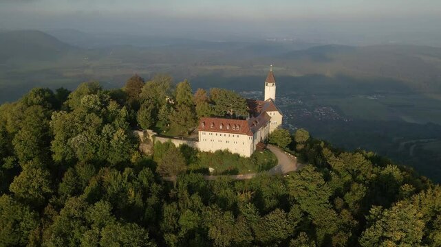 Aerial view of castle, mountain, forest, and trees at sunrise in Swabian Alps, Burg Teck, Germany.