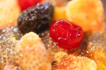 Macro view of a fruit salad with banana, cherry, raisin, orange and chia seed.
